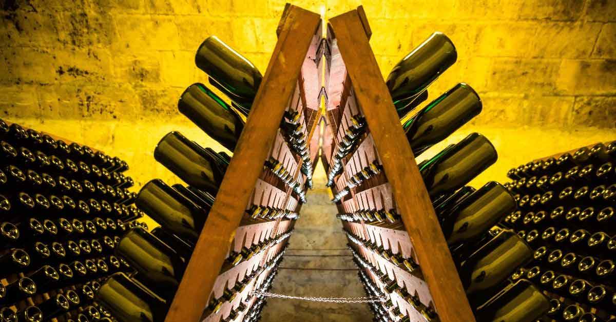 香檳瓶陳放在酒窖的 riddling rack 上，展示香檳傳統除渣陳年工藝與專業儲存方式